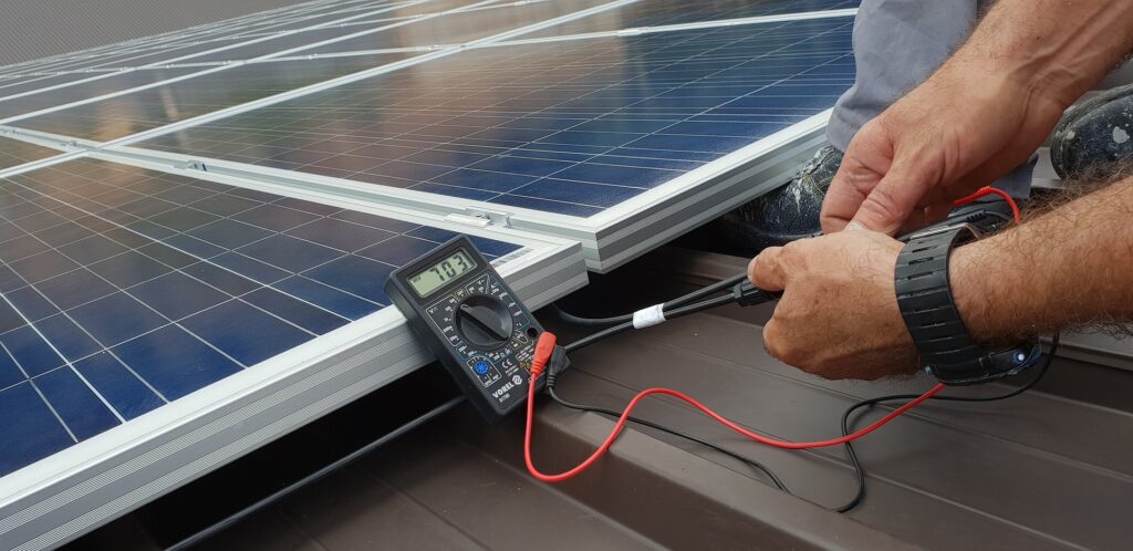 Tecnico che misura la tensione di un pannello solare utilizzando un multimetro, con focus sui pannelli fotovoltaici in un'installazione residenziale.